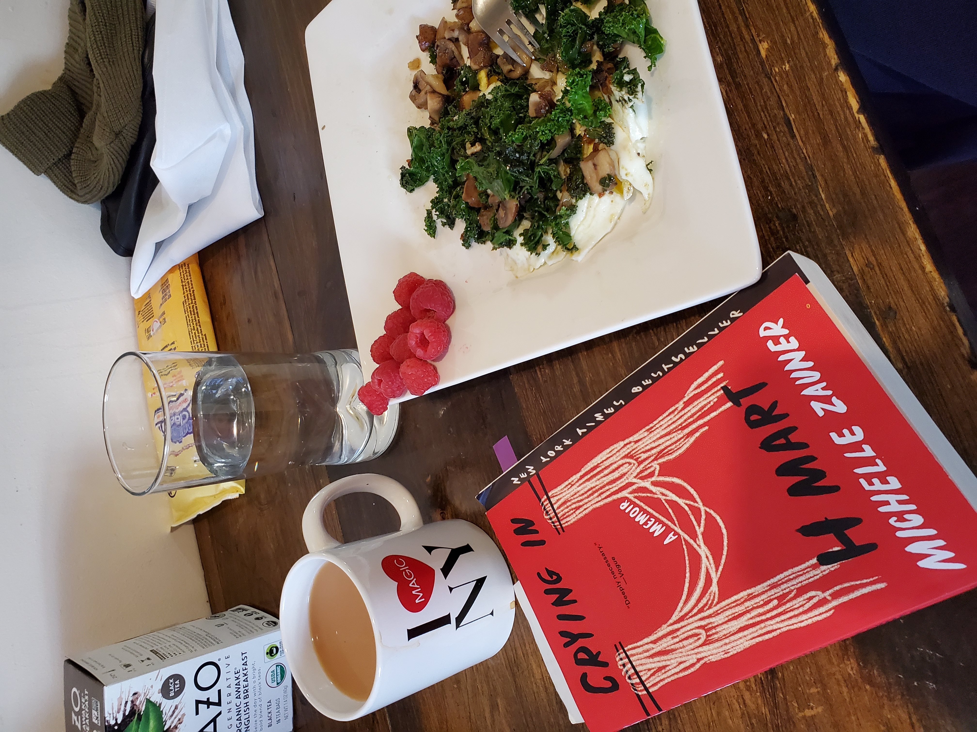 A breakfast scene shows the "Crying in H Mart" book next to a plate of eggs and greens, a cup of tea, and various other items.