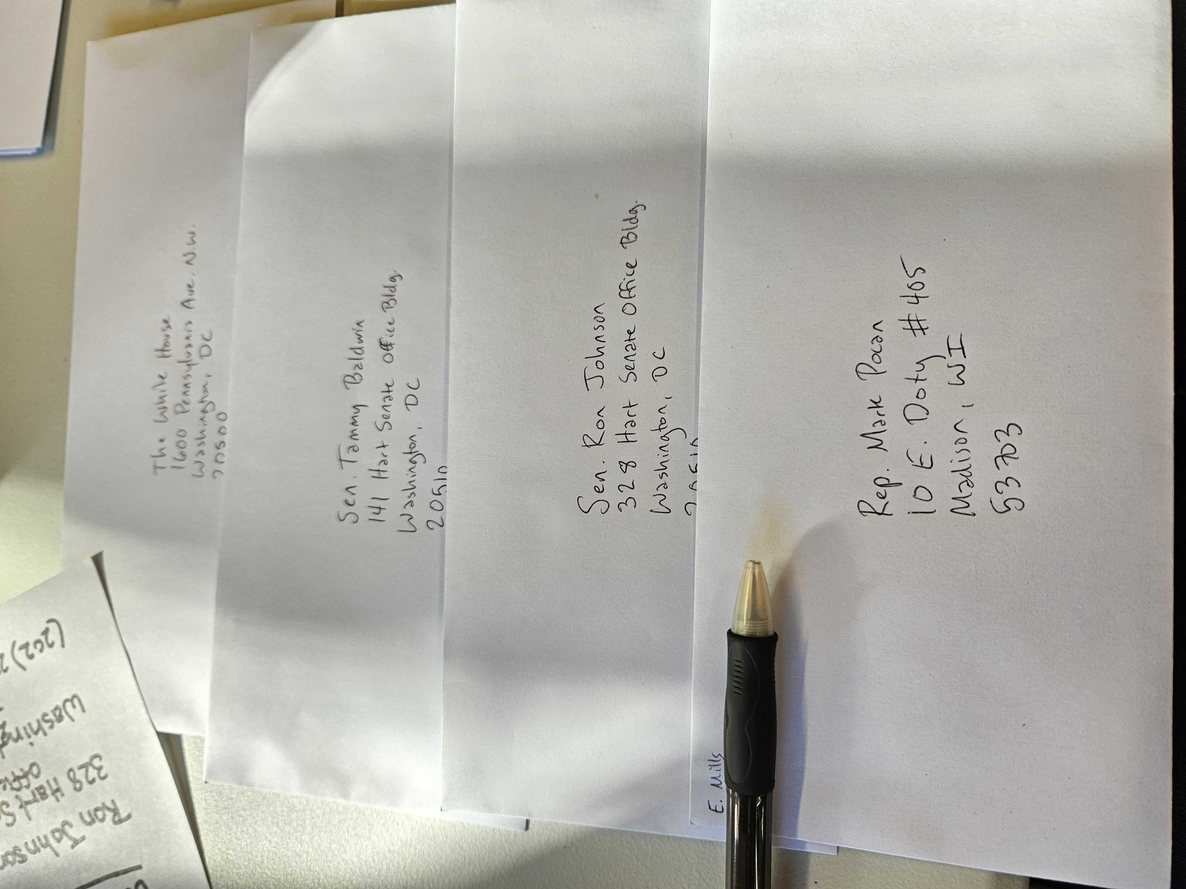 Four white envelopes are hand-addressed to The White House, Sen. Tammy Baldwin, Sen. Ron Johnson, and Rep. Mark Pocan.